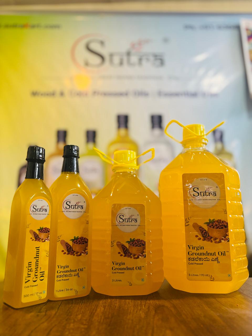 Set of Sutra Virgin Coconut Oil bottles on a wooden surface with a branded backdrop.