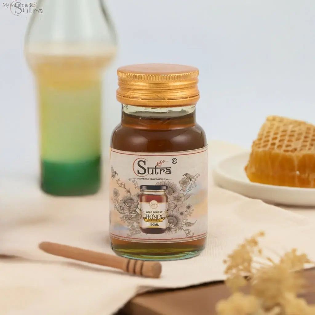 Sutra Wild Forest Honey jar on a table with honeycomb and dipper, symbolizing pure, natural honey for health and wellness.
