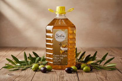 Bottle of Sutra Extra Virgin Olive Oil on a wooden surface with olive leaves and olives.