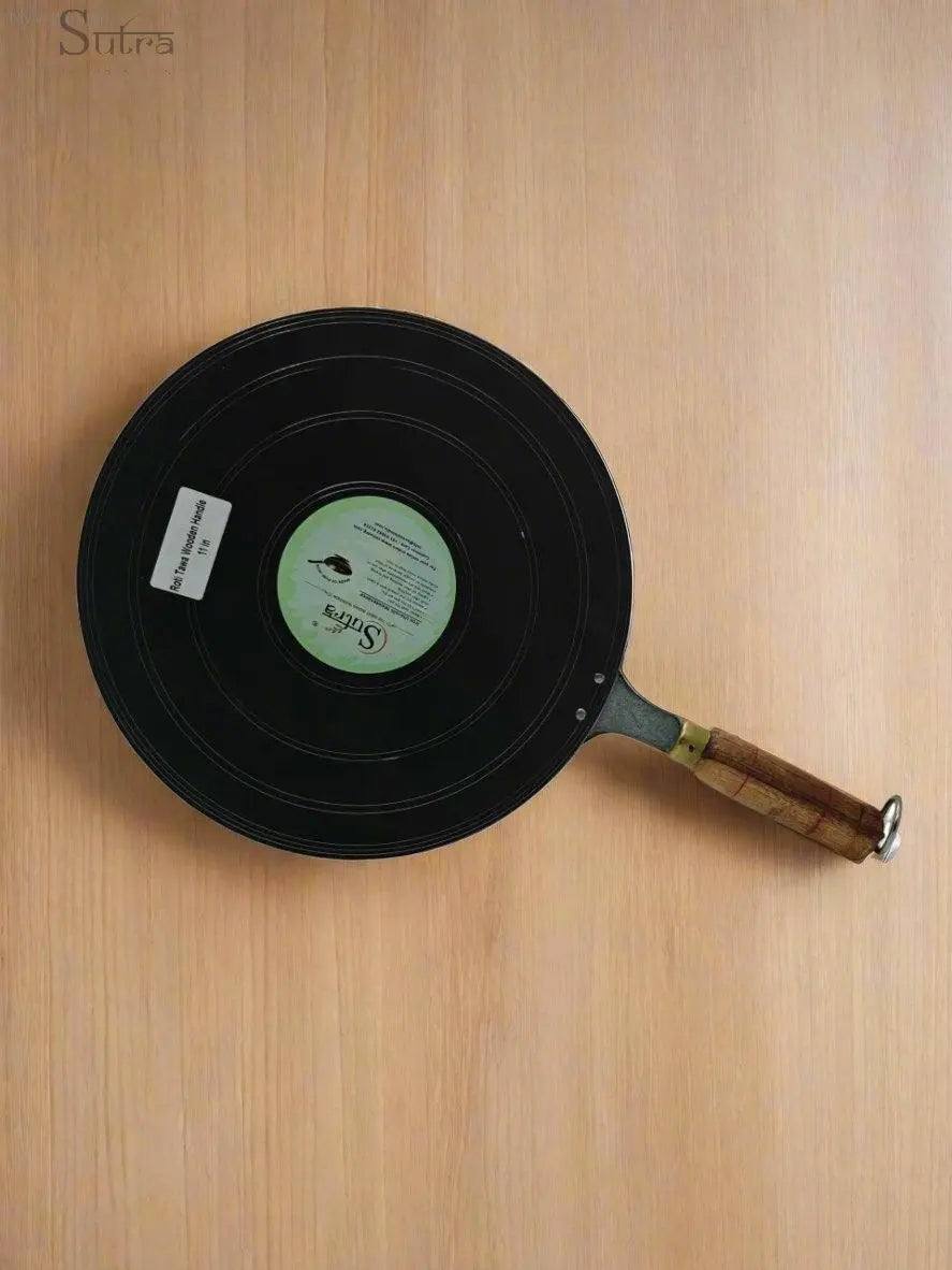 Sutra 100% pure iron roti tawa with wooden handle on wooden surface, ideal for even heat distribution and chemical-free cooking.